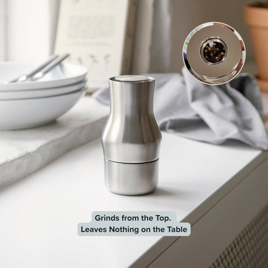 Stainless steel salt grinder on a kitchen counter with bowls and a towel in the background. Gense Dorotea Collection Grinder German Design Award winner
