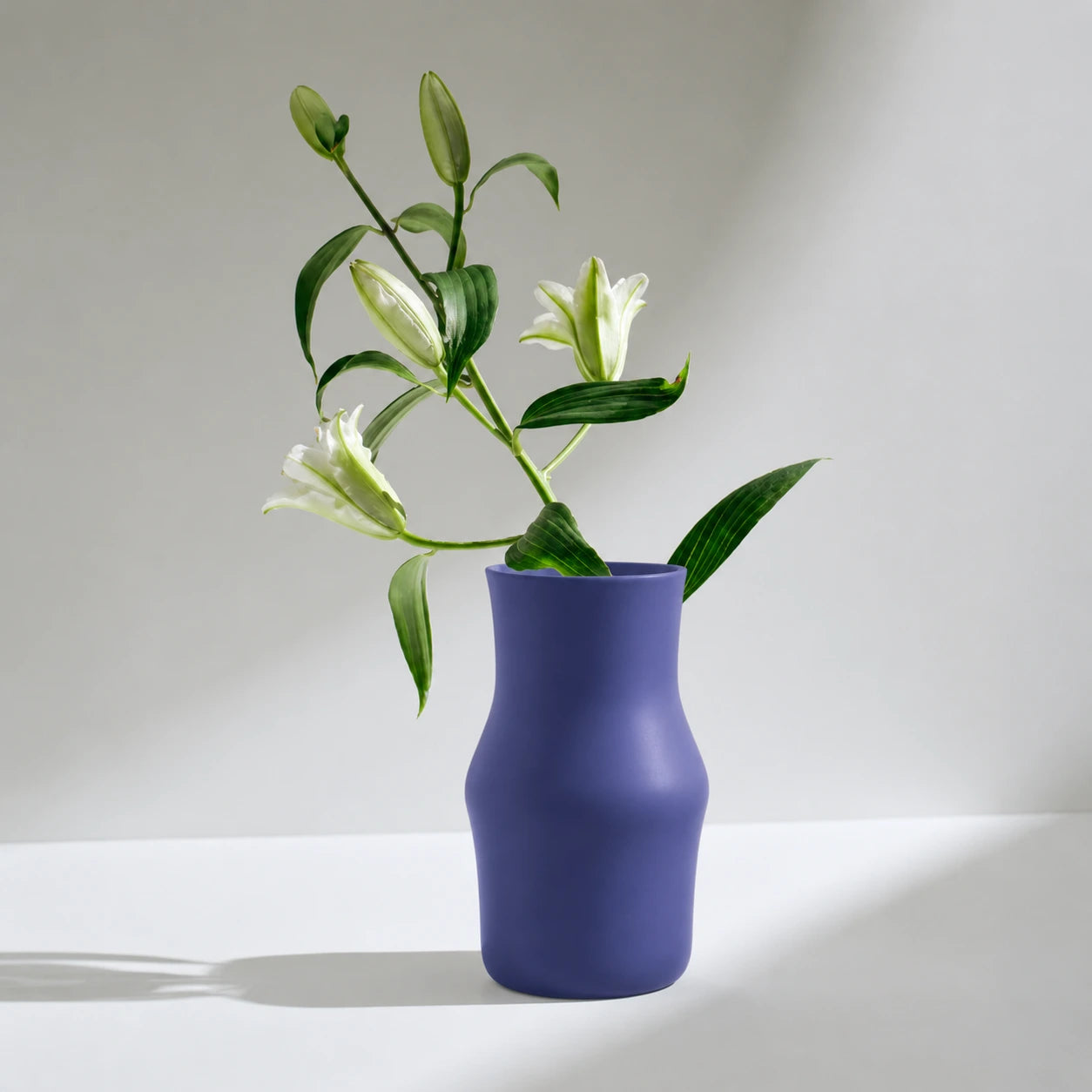 Dorotea Ceramic Blue vase with white flowers on a light gray background