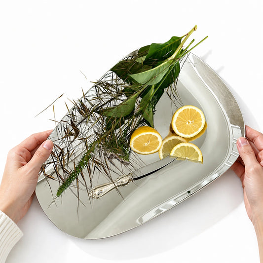 Dorotea Silver tray with lemons and greenery held by hands on a white background