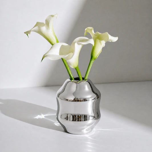 Dorotea Stainless steel vase with white calla lilies on a light surface