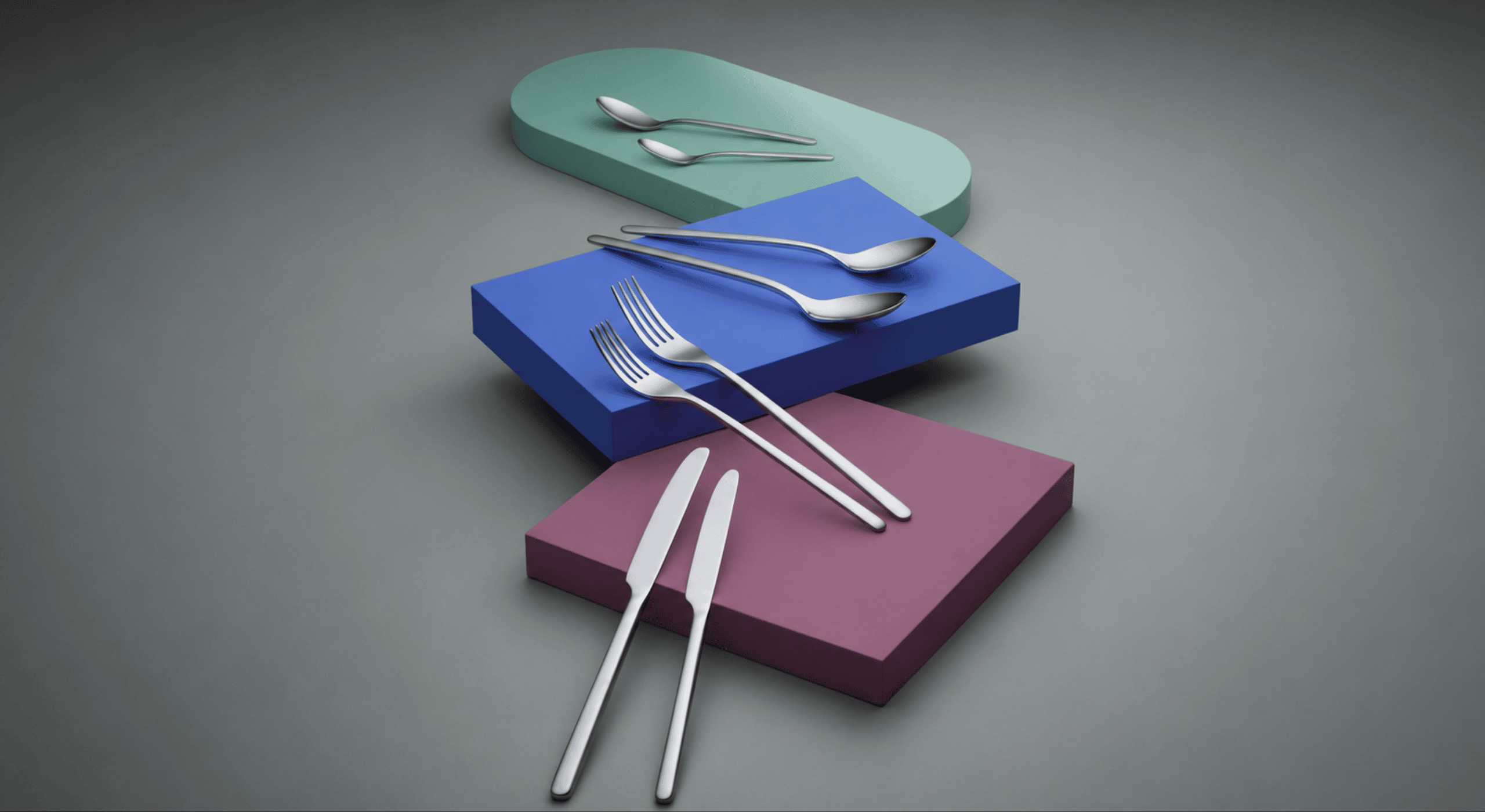 Silver cutlery on colorful geometric blocks against a gray background gense still collection